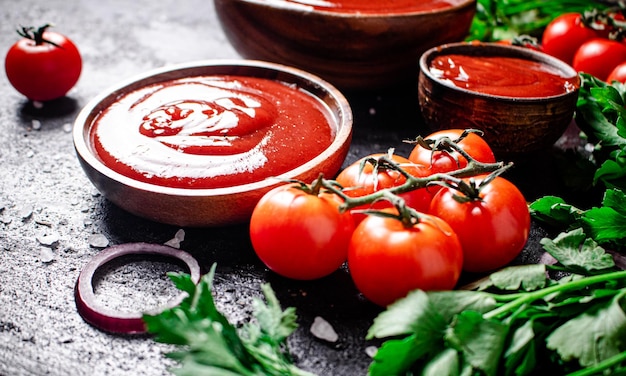 Sos pomidorowy w drewnianym talerzu z krążkami cebuli i ziołami