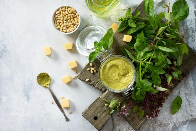 Sos z zielonego pesto, parmezan z bazylią i orzeszkami pinii na stole z kamienia lub łupka