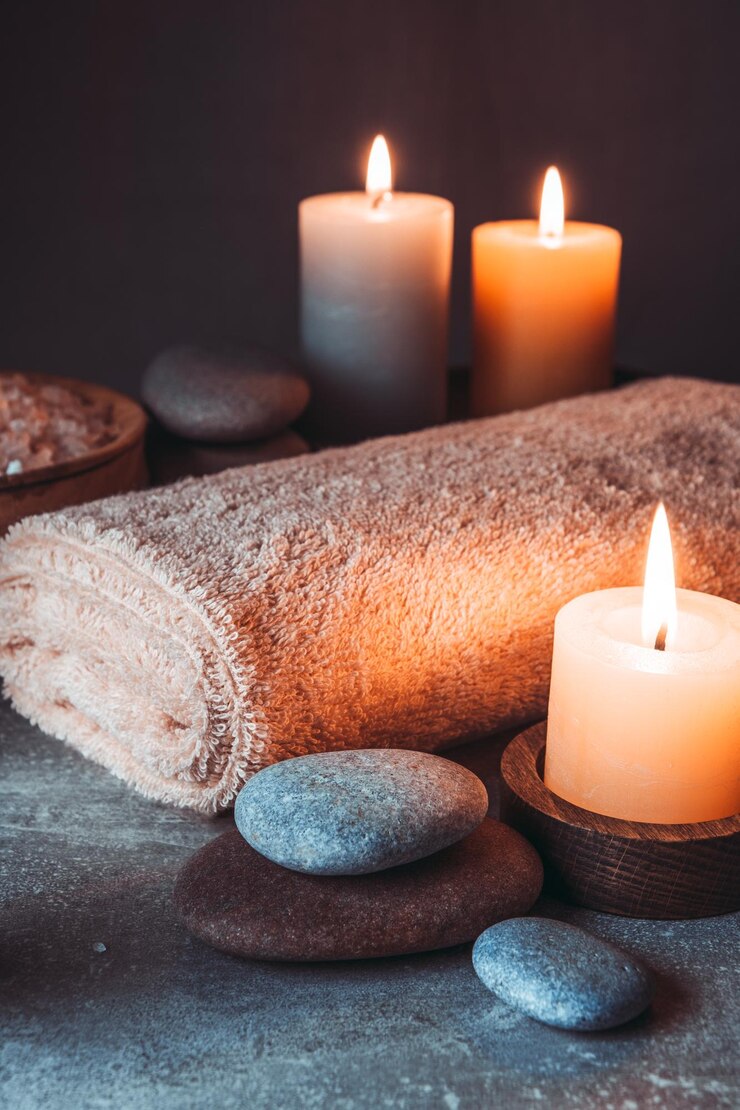 Spa martwe życie ze świecami kamieniami i ręcznikiem na szarym tle