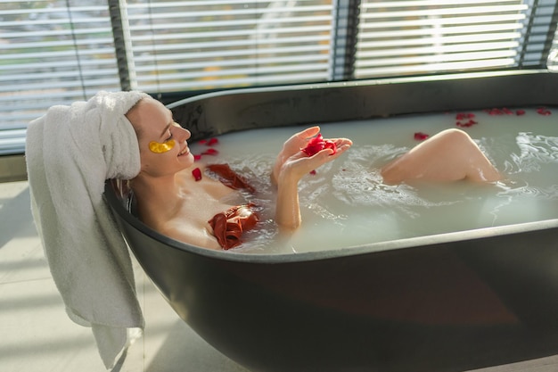 Zdjęcie spa relaksująca kobieta leżąca w wannie z szklanką z czerwonym winem dziewczyna zrelaksująca się w łazience