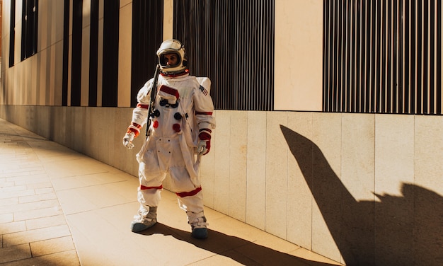 Spaceman na futurystycznej stacji. Mężczyzna w skafandrze kosmicznym spacerujący po obszarze miejskim