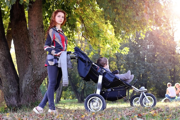 Spaceruj kobiety z wózkiem letnim światłem słonecznym