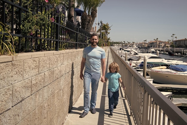 Spacerując razem Promenada ojca i syna trzymających się za ręce Mężczyzna i chłopiec cieszą się spokojnym spacerem