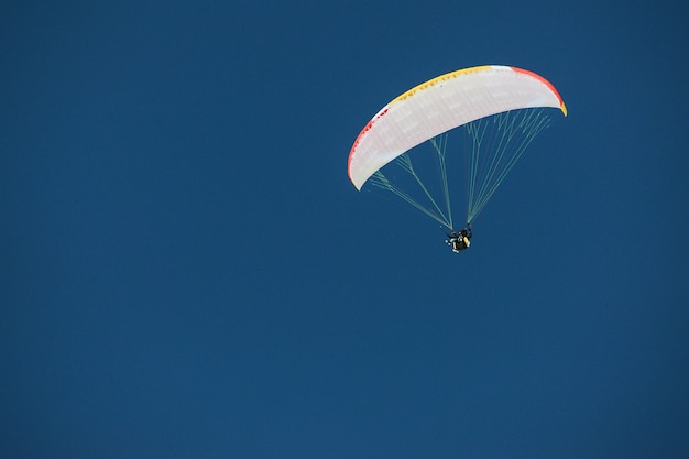 Spadochroniarz pod baldachimem spadochronu na tle błękitnego nieba w Gruzji, Gudauri