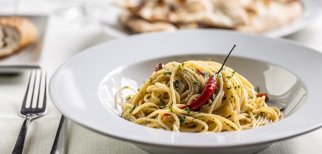 Spaghetti aglio e olio peperoncino z ostrym świeżym chilli podawane na ciemnobiałym talerzu