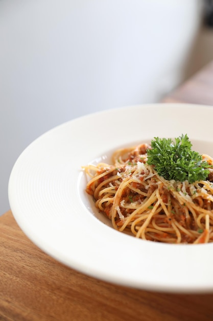 Spaghetti Bolognese z mieloną wołowiną i sosem pomidorowym ozdobione parmezanem i bazylią , włoskie jedzenie