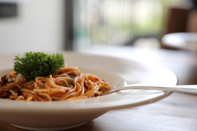 Spaghetti Bolognese z mieloną wołowiną i sosem pomidorowym ozdobione parmezanem i bazylią , włoskie jedzenie