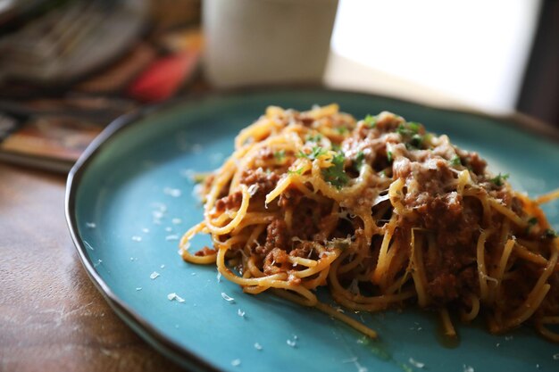 Spaghetti Bolognese z mieloną wołowiną i sosem pomidorowym ozdobione parmezanem i bazylią , włoskie jedzenie