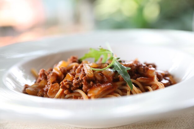 Spaghetti Bolognese z mieloną wołowiną i sosem pomidorowym ozdobione parmezanem i bazylią , włoskie jedzenie