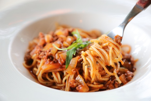 Spaghetti Bolognese z mieloną wołowiną i sosem pomidorowym udekorowane parmezanem i bazylią