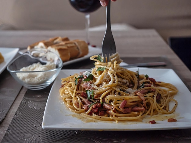 Zdjęcie spaghetti carbonara z serem chlebowym i lampką wina