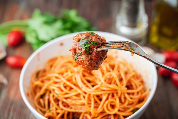 Spaghetti i klopsiki z sosem pomidorowym w misce biały na drewnianym pokładzie rustykalne