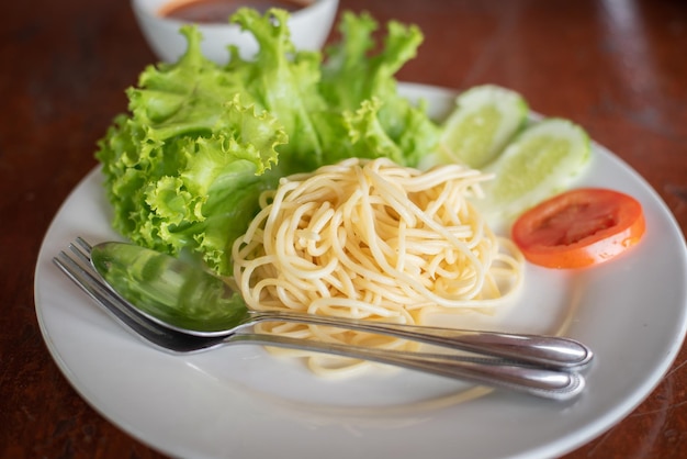 Spaghetti Makaron i sos pomidorowy Czosnek i przyprawy z serem i widelcem na półmisku sałat