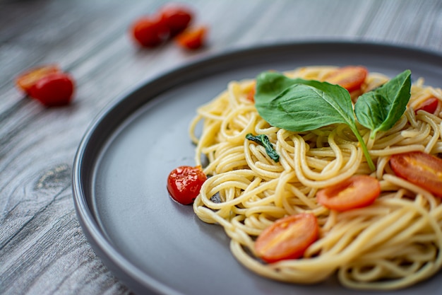 Spaghetti z bazylią i pomidorkami cherry na drewnianym tle