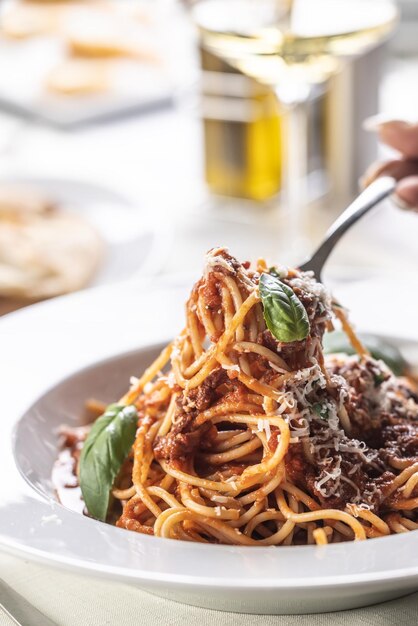 Spaghetti z bazyliowym sosem pomodoro i parmezanem jedzone widelcem