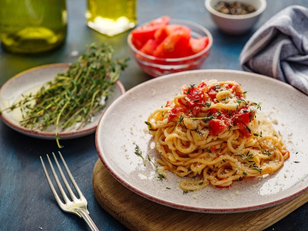 Spaghetti z pomidorami i tymiankiem w talerzu na błękitnym stole