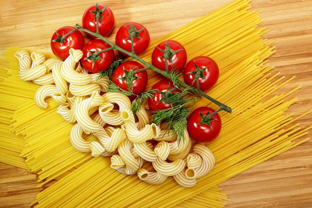 Spaghetti z pszenicy durum i dojrzałe pomidorki koktajlowe na drewnianej bambusowej desce. Zbliżenie. najlepszy