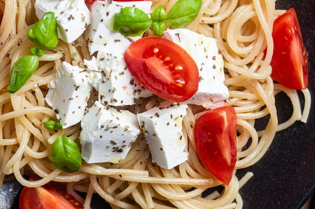 Spaghetti z serem feta i pomidorami na talerzu Włoski makaron