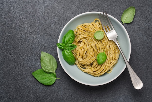 Spaghetti z sosem pesto i bazylią w misce na czarnym tle