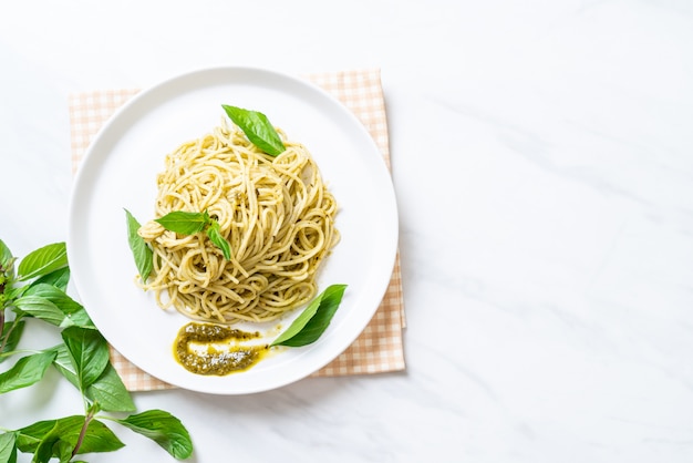 spaghetti z sosem pesto, oliwą z oliwek i liśćmi bazylii.