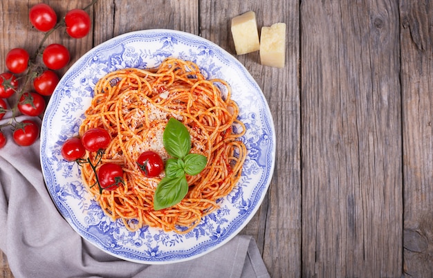 Spaghetti z sosem pomidorowym, pomidorami koktajlowymi, parmezanem drewniany prosty stół