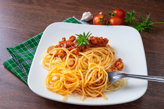 Spaghetti z sosem w naczyniu na drewnianym stole