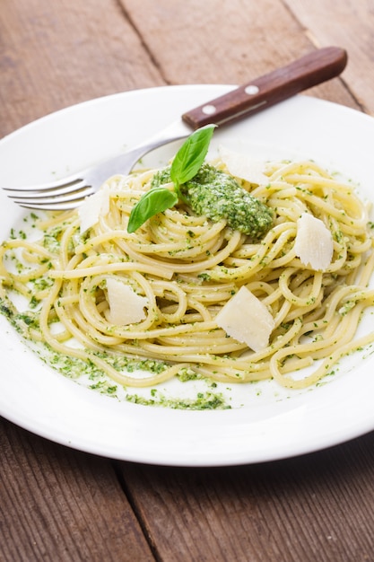 Spaghetti z zielonym pesto i parmezanem na talerzu