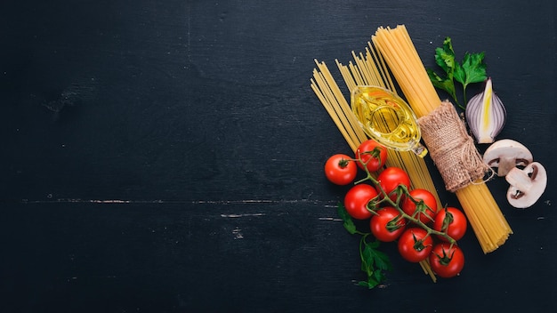 Spaghetti ze świeżymi warzywami i przyprawami. Włoska kuchnia tradycyjna. Na drewnianym tle. Widok z góry. Skopiuj miejsce.