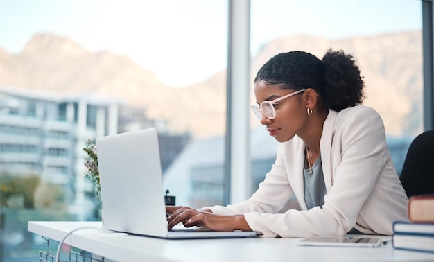 Specjalista ds. danych i sekretarka wpisujący wiadomość e-mail na laptopie i przeprowadzający badania online podczas pracy w biurze Afrykański przedsiębiorca wyglądający na skoncentrowany podczas korzystania z Internetu w pracy