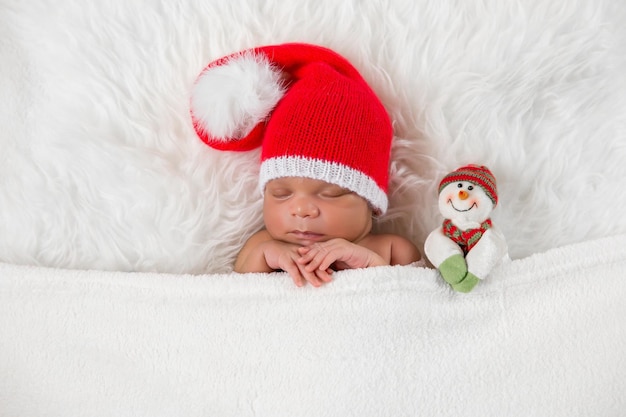 Śpiący noworodek w świątecznej czapce Mikołaja