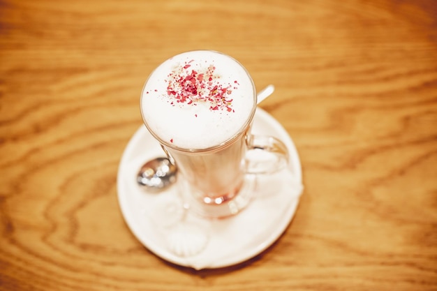 Spienione, warstwowe cappuccino w przezroczystym szklanym kubku z cynamonem posypanym na wierzchuCzas na kawę pyszny słodki napójFresh Energy Aromatic Barista Morning Breakfast DrinkLatte Macchiato with Cocoa Powder