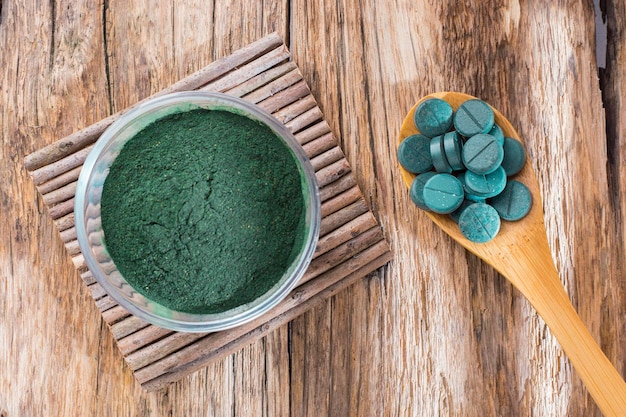 Spirulina w proszku i tabletki na drewnianym tle