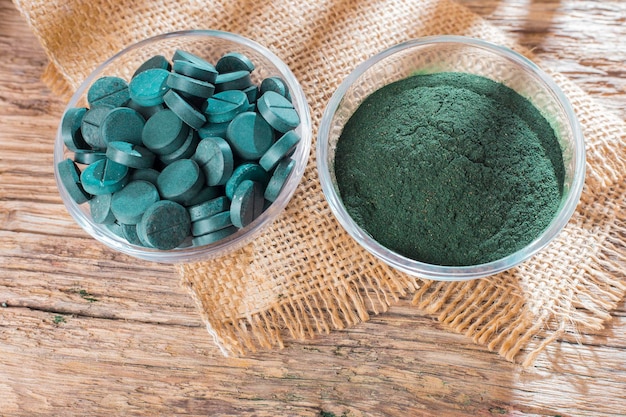 Spirulina w proszku i tabletki na drewnianym tle