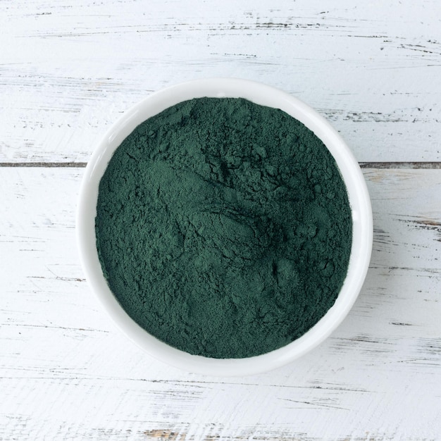 Spirulina w proszku z alg w misce na drewnianym stole.