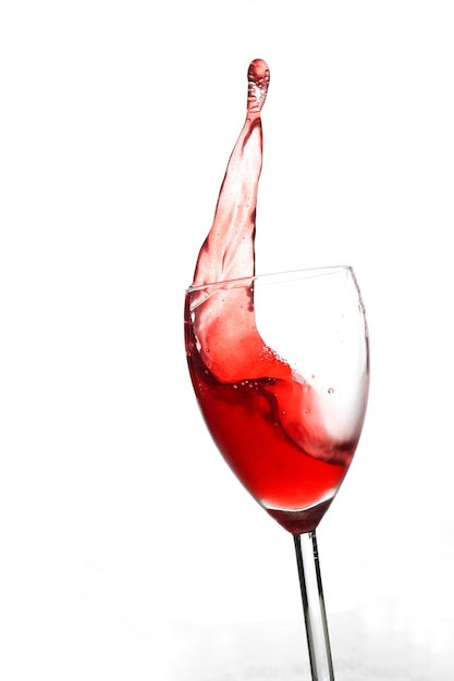 Splash czerwonego wina w szklanym kielichu na białym tle