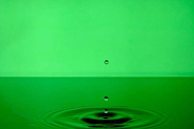 Splash wody po kropli. Zielone tło z kropli w wodzie.