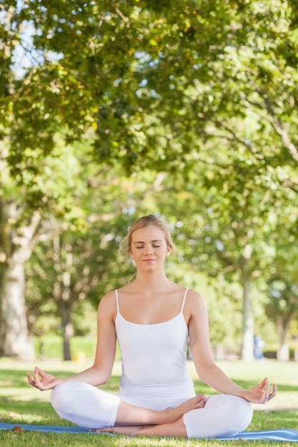 Spokojna kobieta siedzi medytacji na matę do ćwiczeń