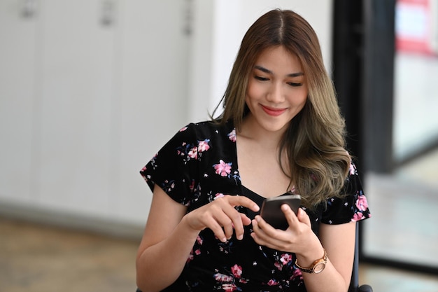 Spokojna młoda kobieta robi zakupy online, sprawdzając media społecznościowe na swoim smartfonie