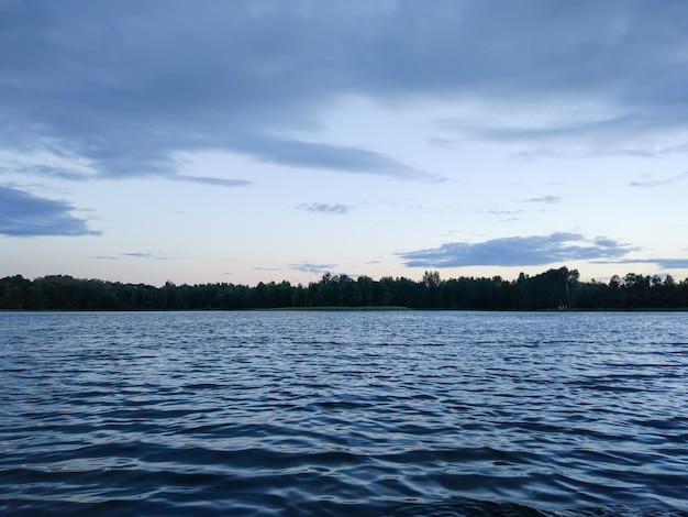 Spokojna powierzchnia jeziora wieczorem na Łotwie, w Europie Wschodniej. lato zachód krajobraz z wody i lasu.