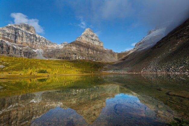 Spokojna scena nad jeziorem górskim w Kanadzie z odbiciem skał w spokojnej wodzie.