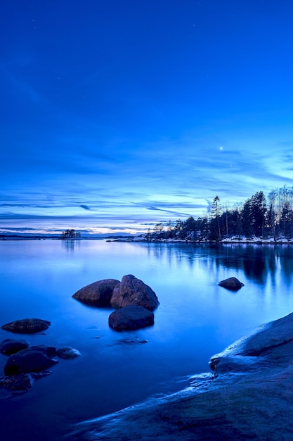 Spokojny zimowy wieczór z pełnią księżyca odbijającą się od spokojnego jeziora