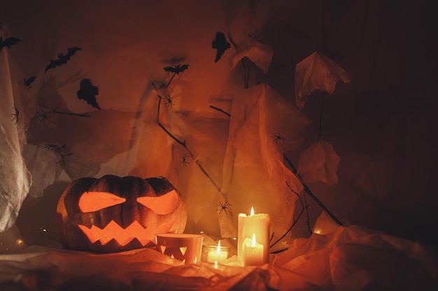 Spooky Jack o latarnia wyrzeźbiona dynia pajęczyna nietoperze duchy i świecące światło w ciemności Wesołego Halloween Straszny atmosferyczny dekoracje na imprezę halloweenową miejsce na tekst Cukierek albo psikus