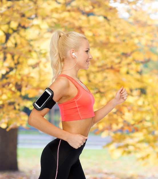 sport, ćwiczenia, technologia, internet i opieka zdrowotna - uśmiechnięta wysportowana kobieta biega i słucha muzyki ze smartfona