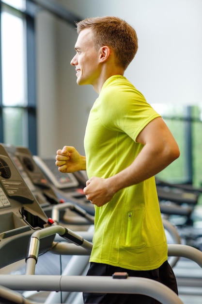 sport, fitness, styl życia, technologia i koncepcja ludzi - uśmiechnięty mężczyzna ćwiczący na bieżni w siłowni