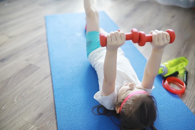 Sport i zdrowy styl życiaDziecko uprawiające sport w domu Mata do jogi, hantle i skakanka Sportowe tło z koncepcją ćwiczeń domowych