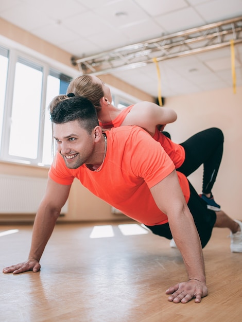 Sport szczęśliwy trening podnosi razem koncepcja siłowni. Wesołe i owocne wspólne ćwiczenia fitness.