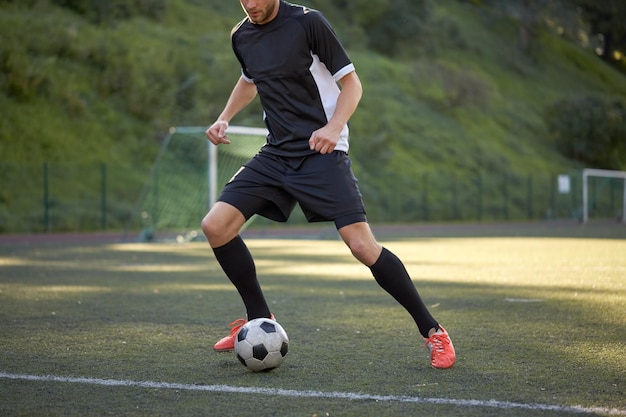 sport, szkolenie piłkarskie i ludzie - piłkarz grający piłką na boisku