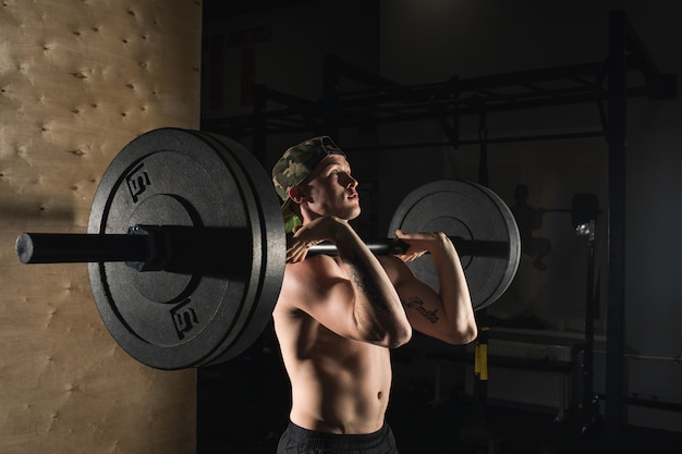 Sport, trening. Zbliżenie portret mięśniowy mężczyzna trening z barbell przy gym.