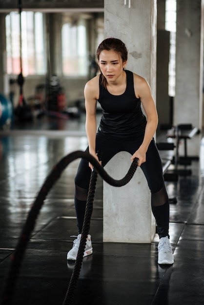 Sportowa azjatykcia kobieta ćwiczy z batalistyczną arkaną przy gym