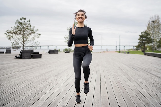 Sportowa biegaczka używa zegarka fitness do treningu ubranego trenera biegania